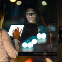 Business woman taking a break while checking her digital tablet standing in the office at night